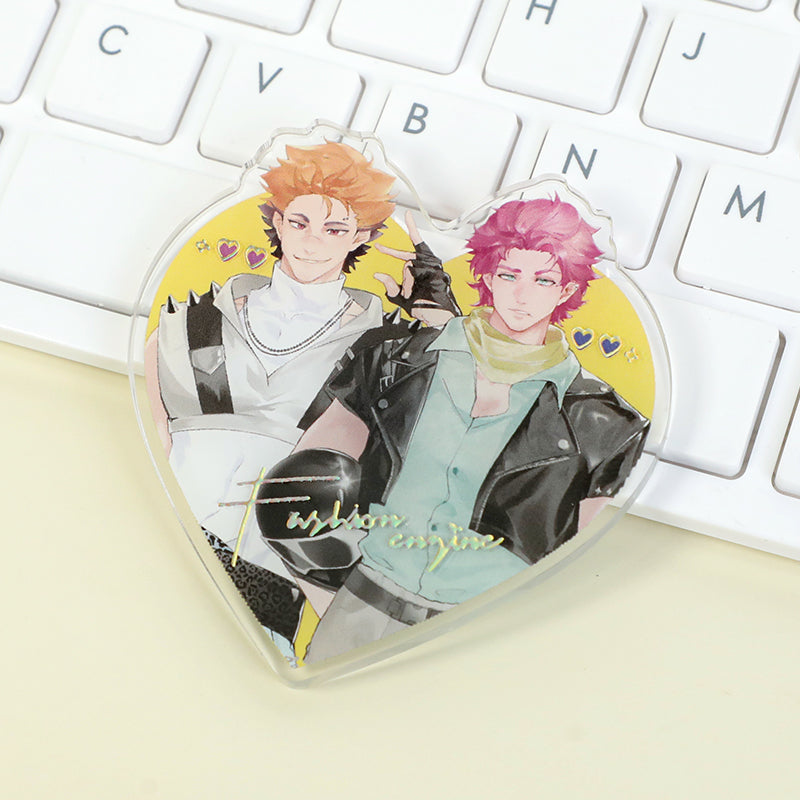 Custom clear acrylic fridge magnet with raised foil stamping, featuring two anime characters on a yellow heart-shaped background, placed on a keyboard.